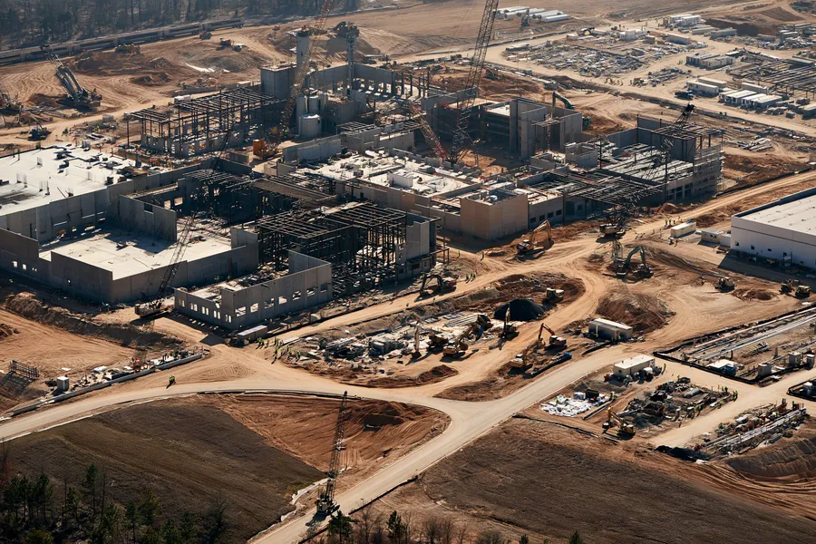 Aerial view of a large construction site with steel frames, cranes and earthmoving equipment