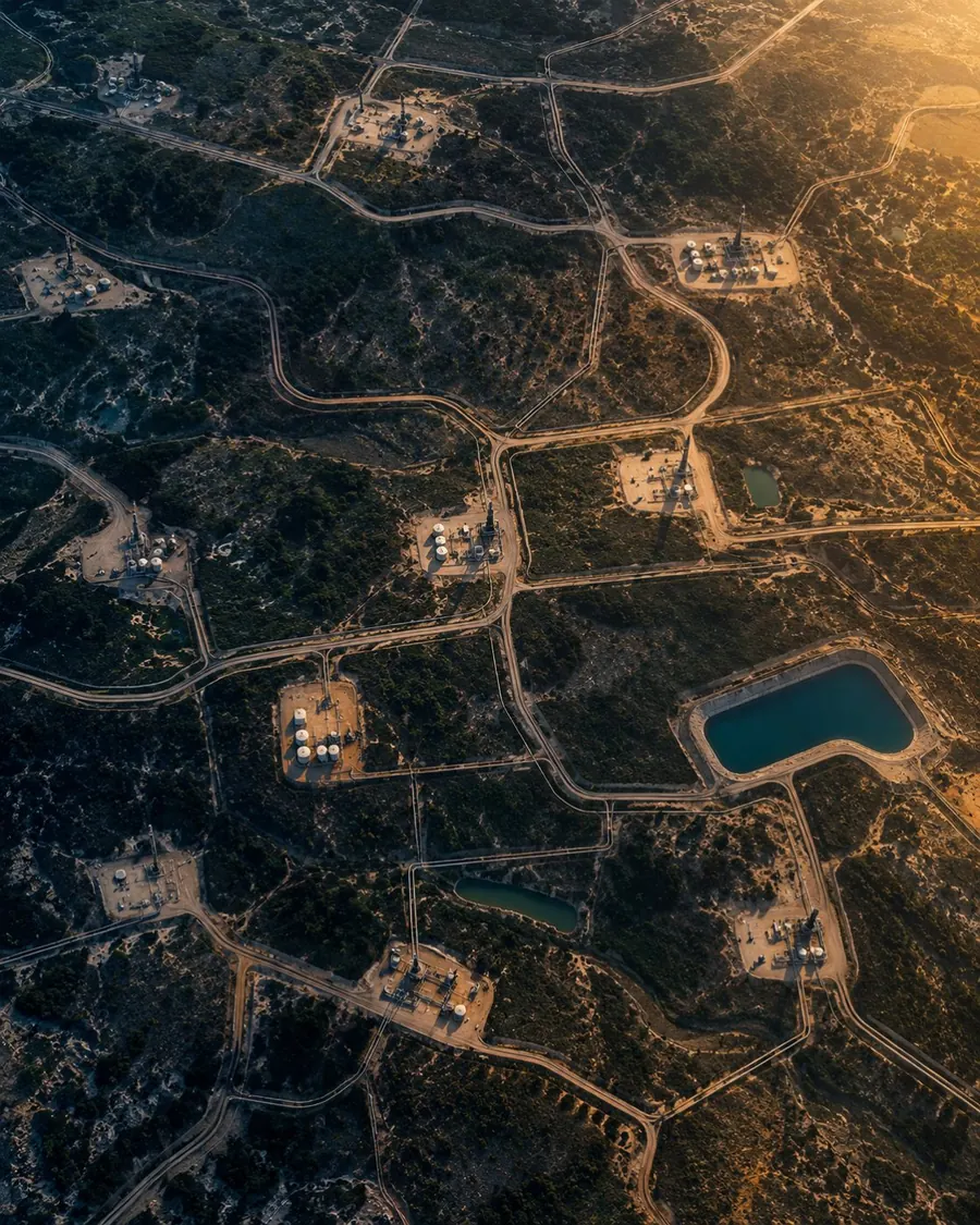 Aerial view of oil and gas well pads connected by roads across desert scrub